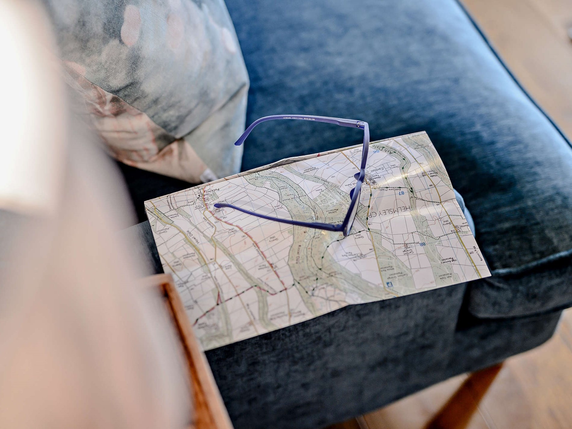 a map and glasses sitting on a blue couch at 2 Bed in Brandsby 91540 in Brandsby